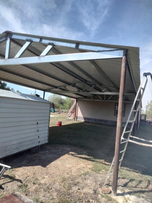 A metal carport is being built in the backyard of a house.