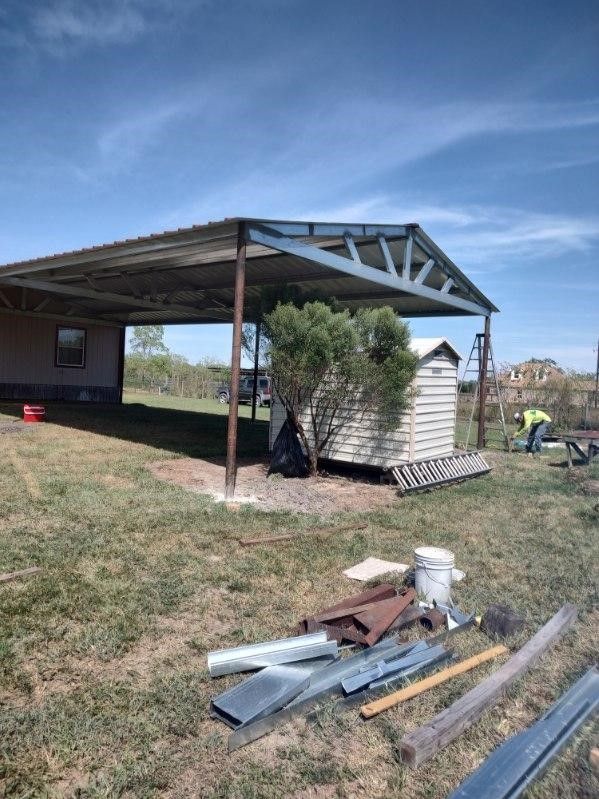 A metal shed is being built in a grassy field.