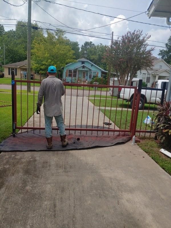 A man is standing in front of a gate in a driveway.