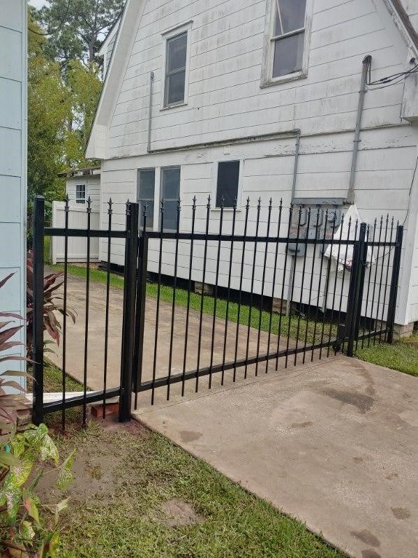 A black wrought iron fence is in front of a white house.