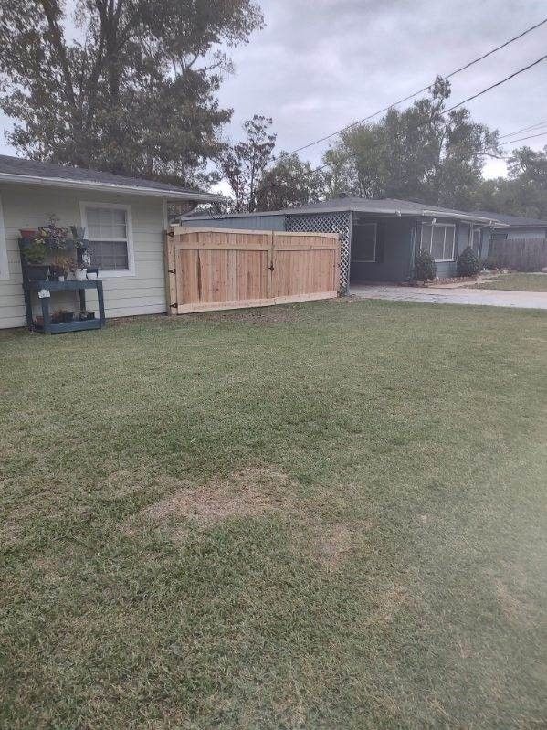 A wooden fence is in the backyard of a house.