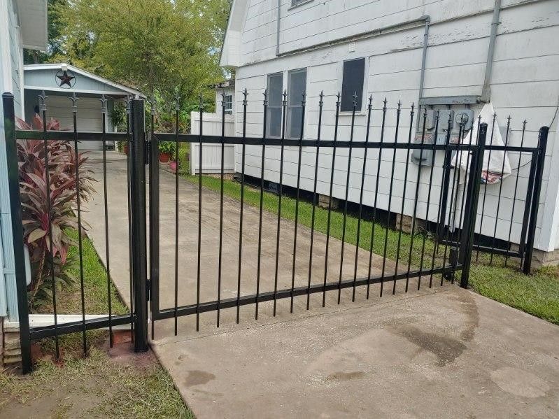 A black wrought iron gate is sitting in front of a white house.