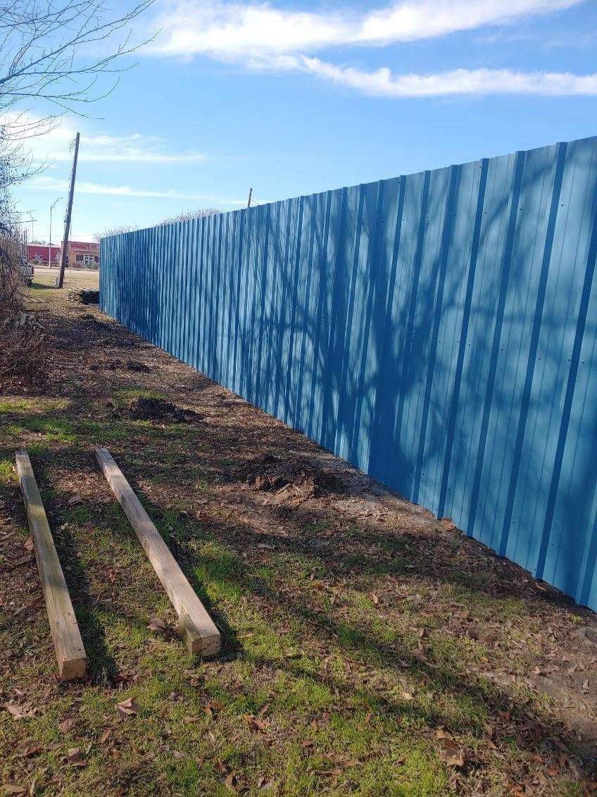 A blue fence is sitting in the middle of a grassy field.