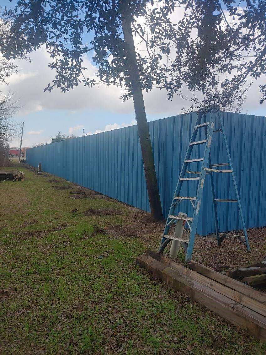 A blue ladder is leaning against a blue fence.