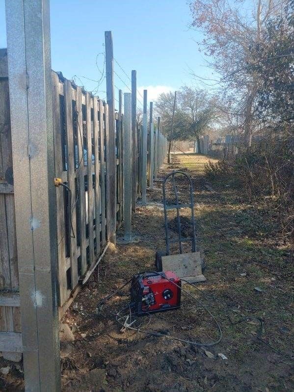 A red generator is sitting next to a wooden fence.