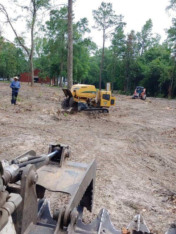 A yellow tractor is sitting in the middle of a dirt field.