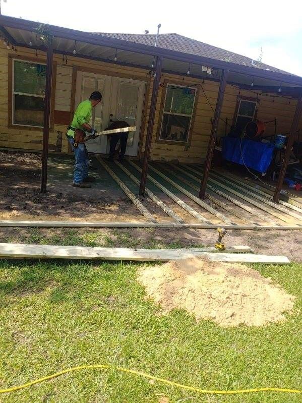 A man is cutting wood in front of a house.
