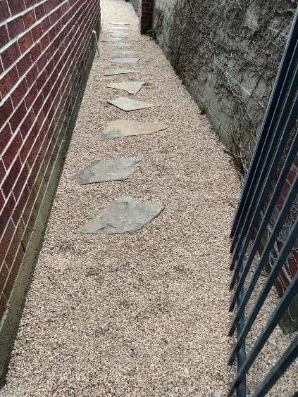 There is a stone walkway between two brick buildings.
