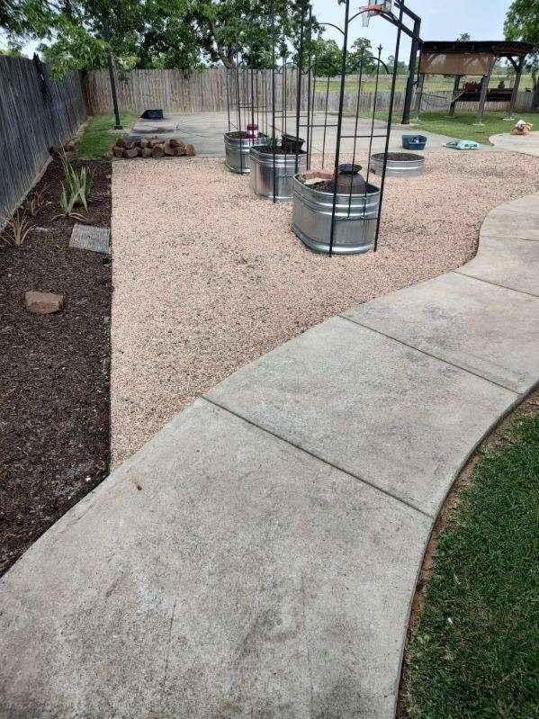 A concrete walkway leading to a basketball court with a basketball hoop in the background.