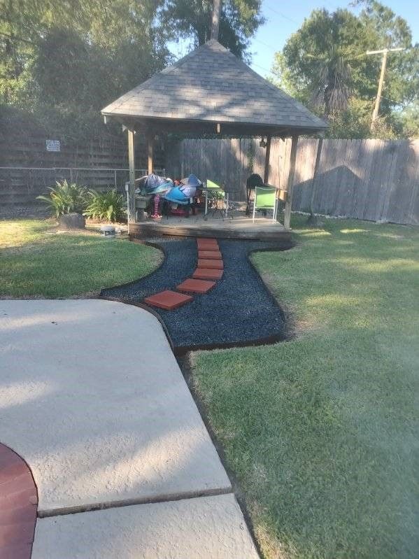 A gazebo in a backyard with a path leading to it