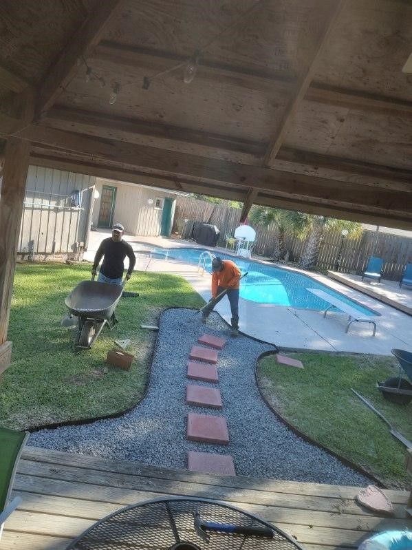 A man is pushing a wheelbarrow in a yard next to a pool.