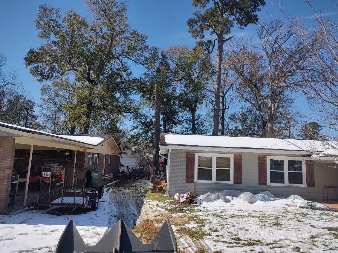A house with snow on the roof and trees in the background.