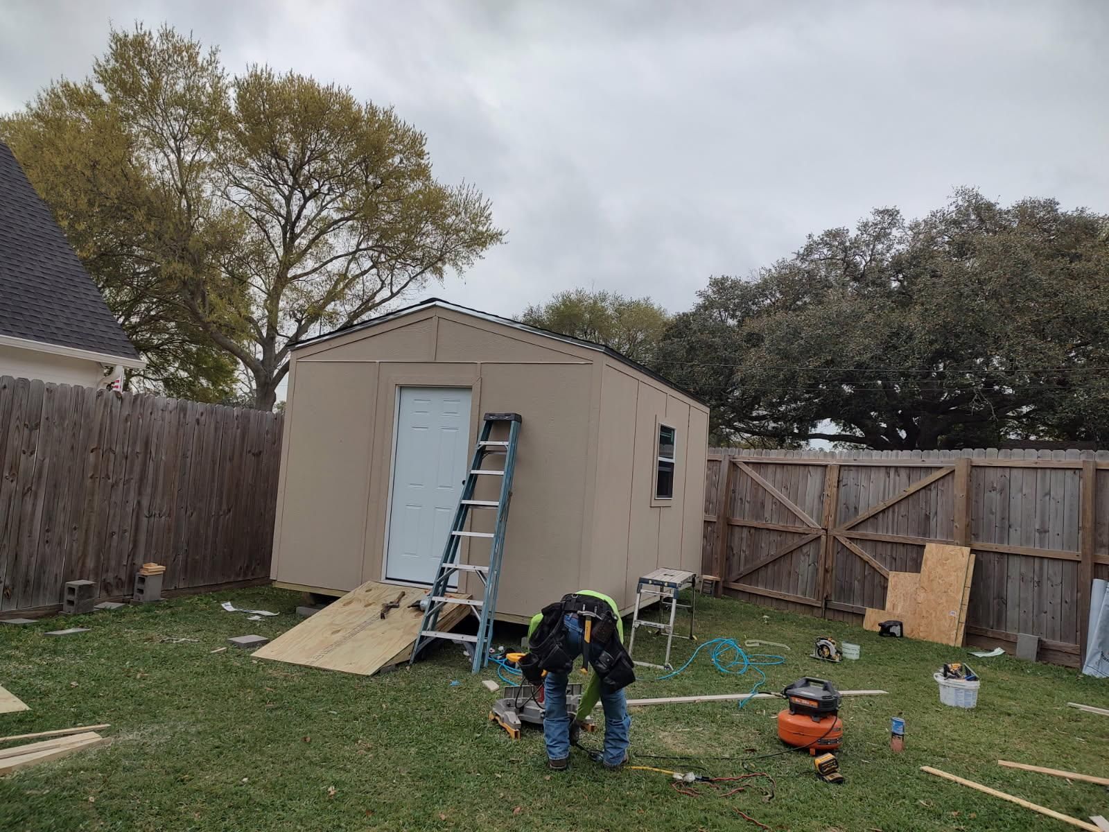 A man is working on a shed in a backyard.