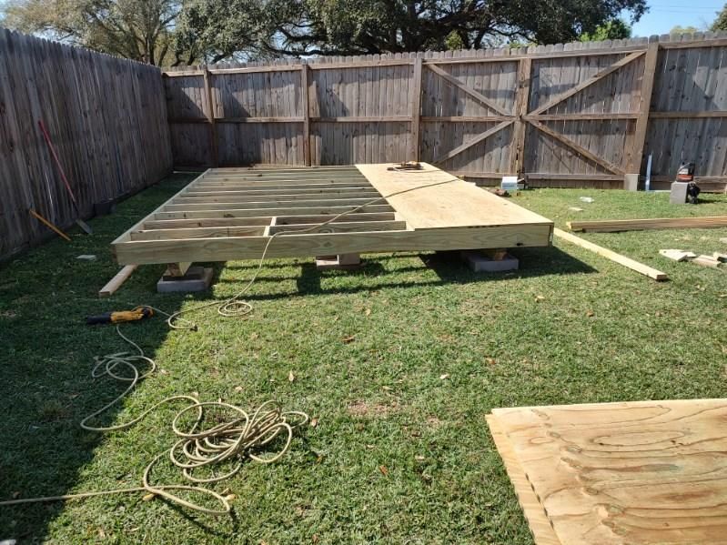 A wooden deck is being built in a backyard