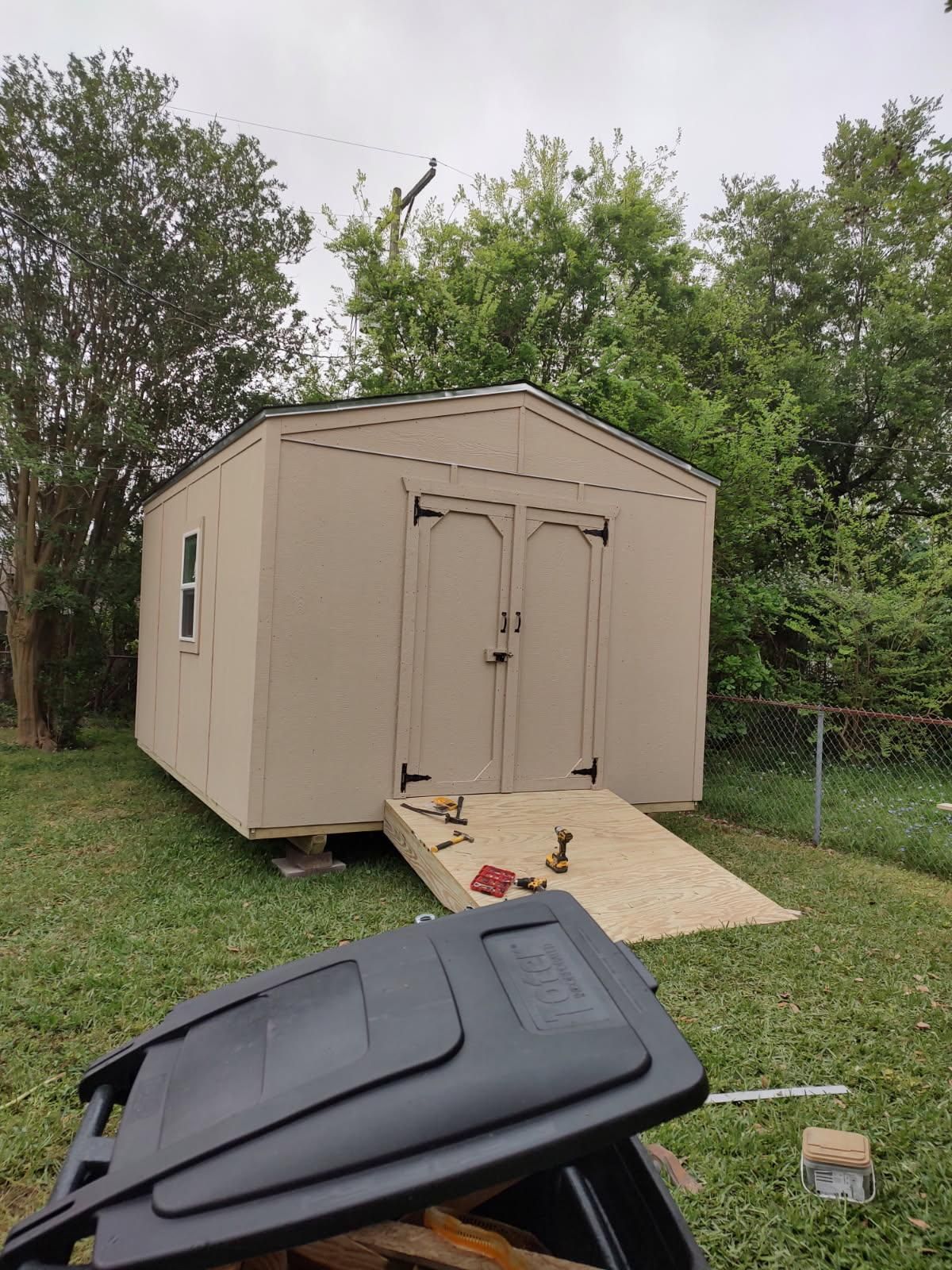 A shed is being built in a backyard next to a trash can.