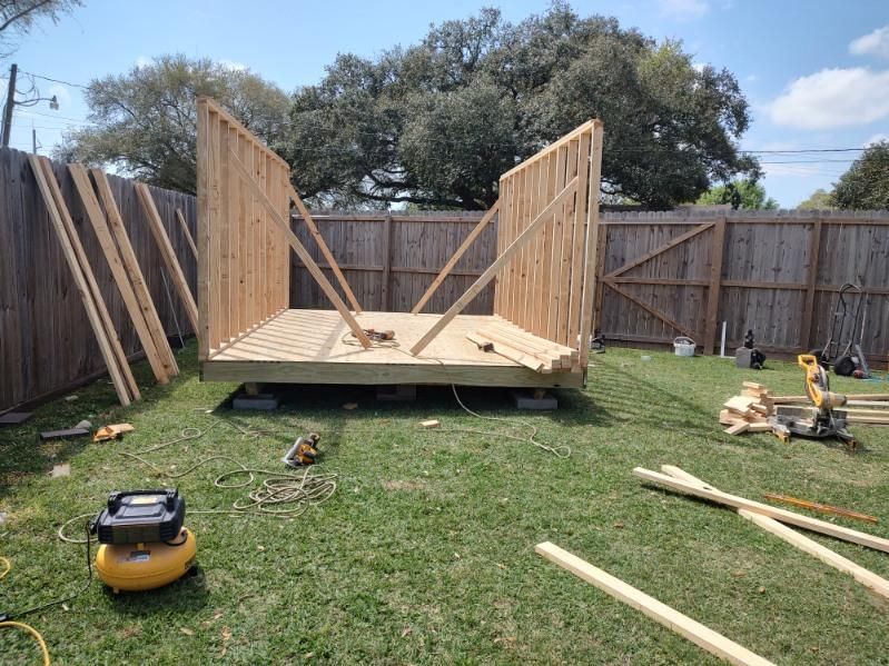 A wooden shed is being built in a backyard.