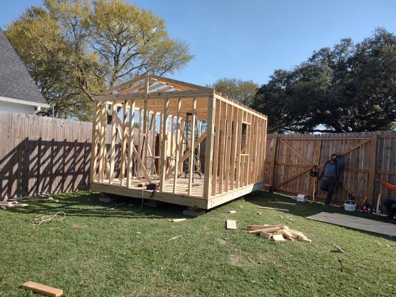 A wooden shed is being built in a backyard.