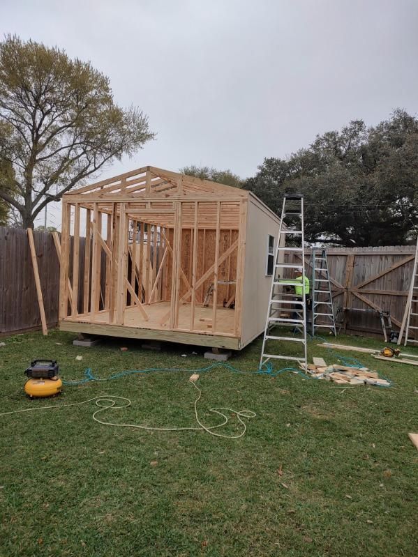 A wooden shed is being built in a backyard.