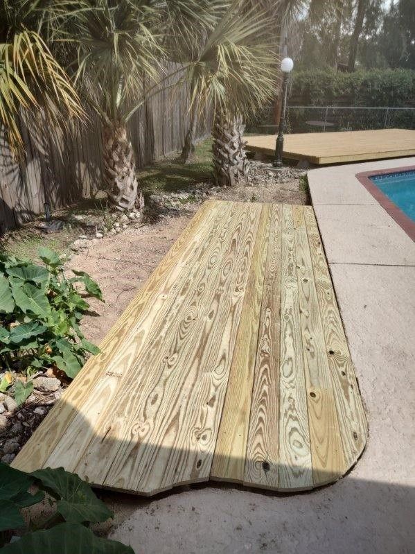 A wooden deck is sitting next to a swimming pool.