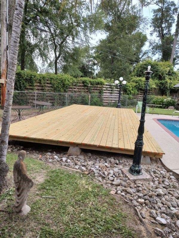 A wooden deck is sitting next to a swimming pool.