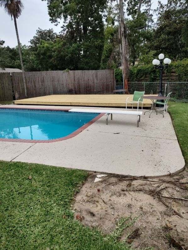 A swimming pool with a wooden deck in the backyard.