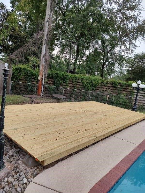 A wooden deck is sitting next to a swimming pool.