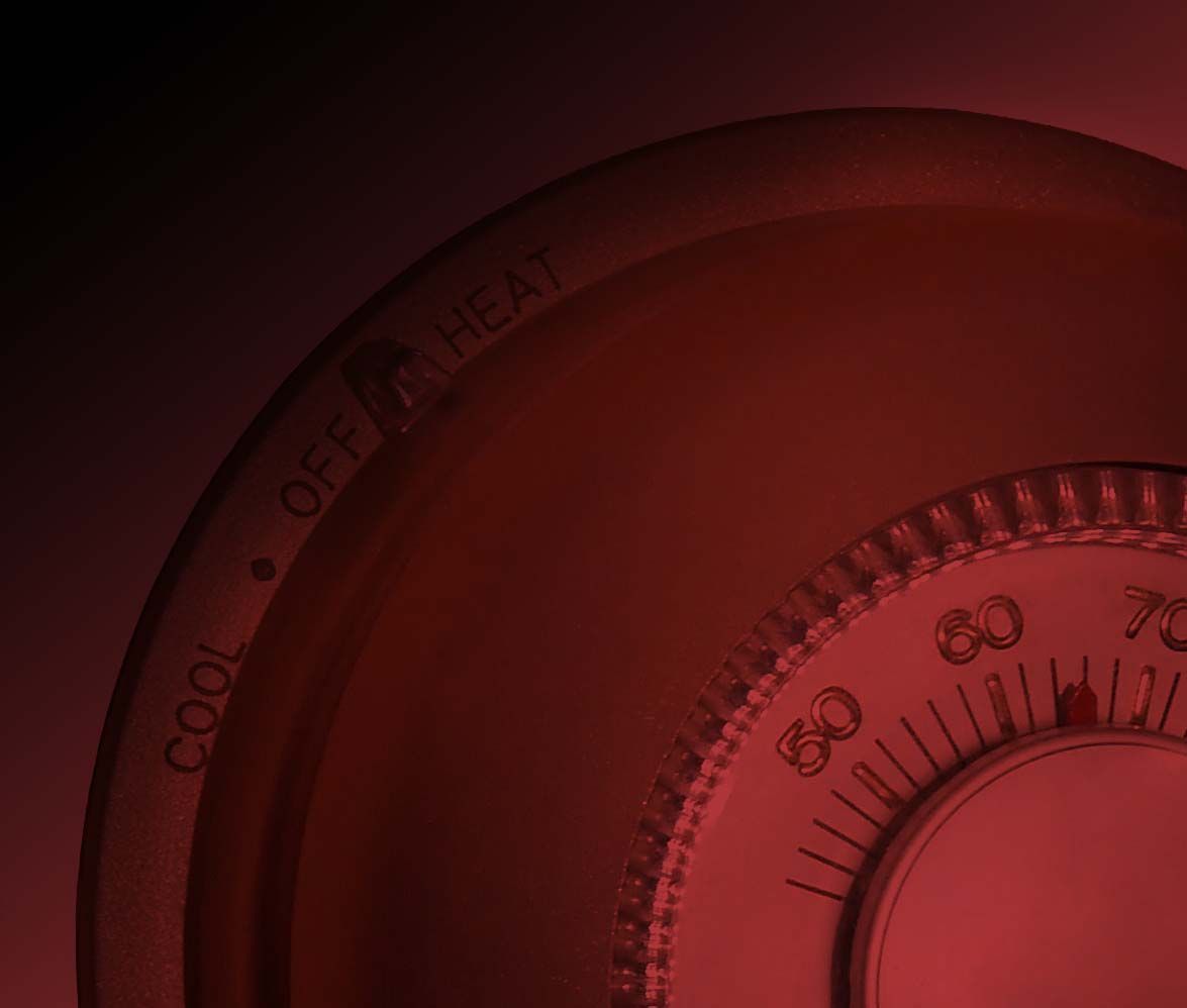 Close-up of a circular thermostat dial with settings for cool, off, and heat. Numbers visible on dial.