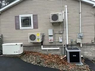 Exterior of a house with air conditioning units, generator, and electrical boxes.