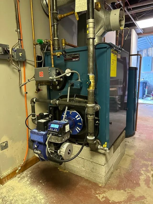 A blue oil-fired boiler with connected pipes and exhaust in a utility room.