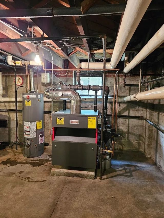 Basement with water heater, furnace, copper pipes, and exposed ceiling. Concrete floor and stone walls.