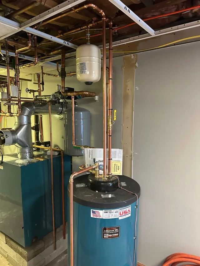 Copper pipes and tanks, part of a water heating system in a basement.