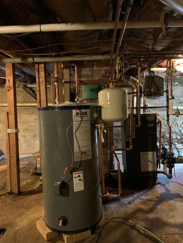Water heater, copper pipes, and related equipment in a basement.