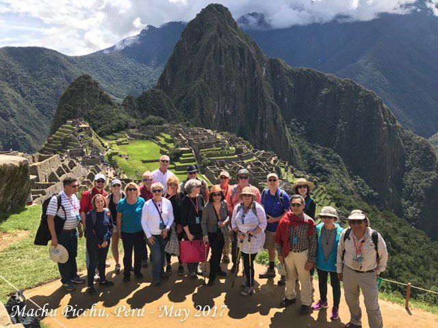 A group of people standing in front of a mountain in peru
