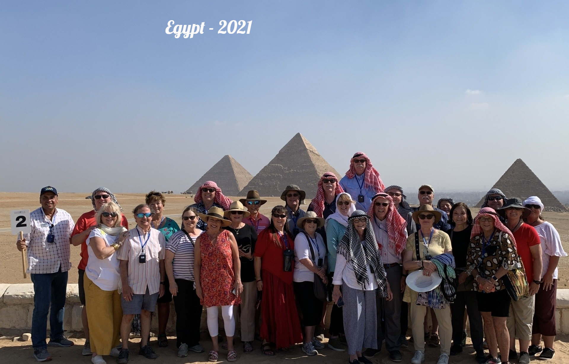 A group of people are posing for a picture in front of the pyramids in egypt.