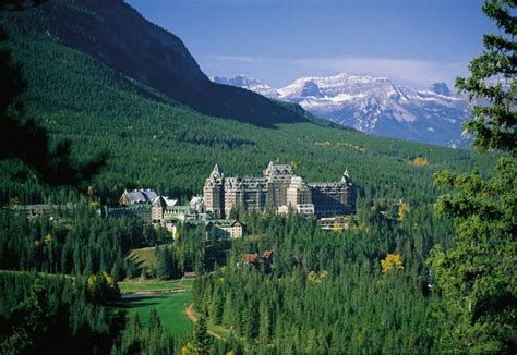 Fairmont Banff Springs Hotel nestled in a valley of evergreen trees with mountains in the background.