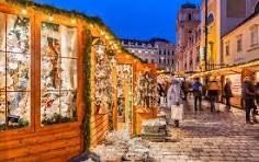 A group of people are walking down a cobblestone street at a christmas market.