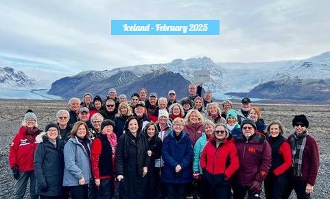 A large group of people are posing for a picture in front of a mountain.