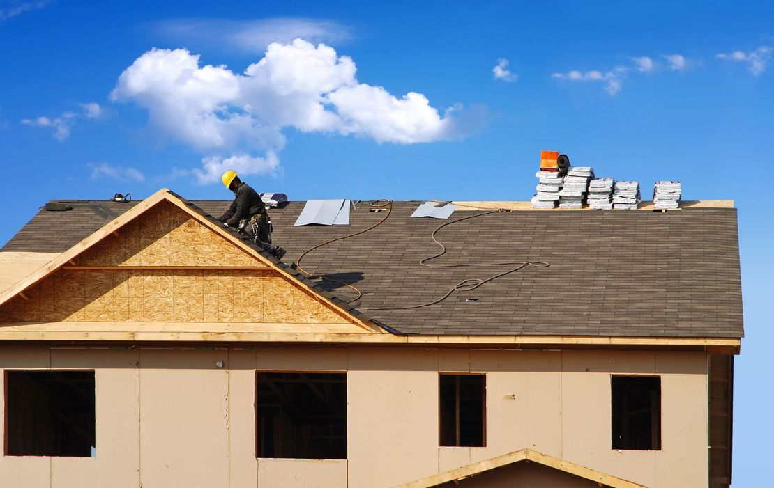 Partially built wooden houses at a construction site under clear skies