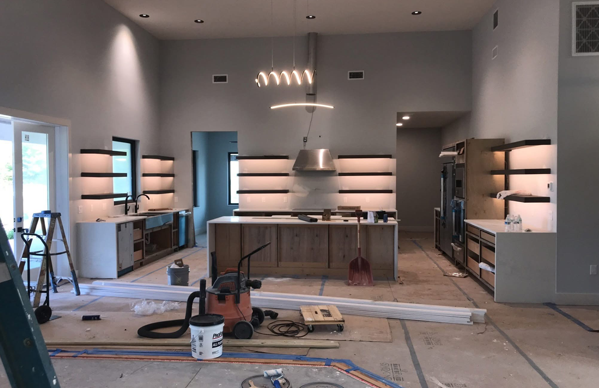 Modern kitchen under construction with cabinets, island, tools, and unfinished floors