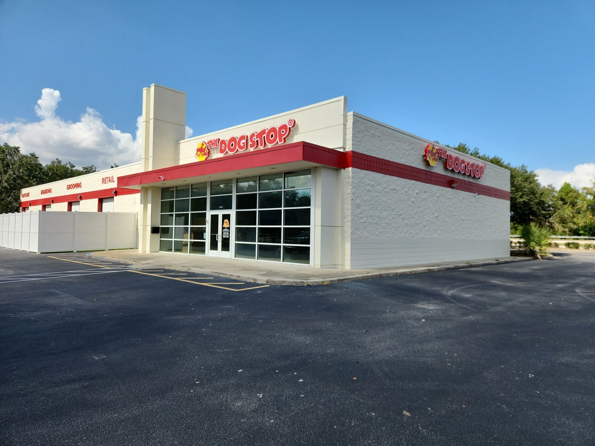 White auto service storefront with red trim and large glass windows under a blue sky
