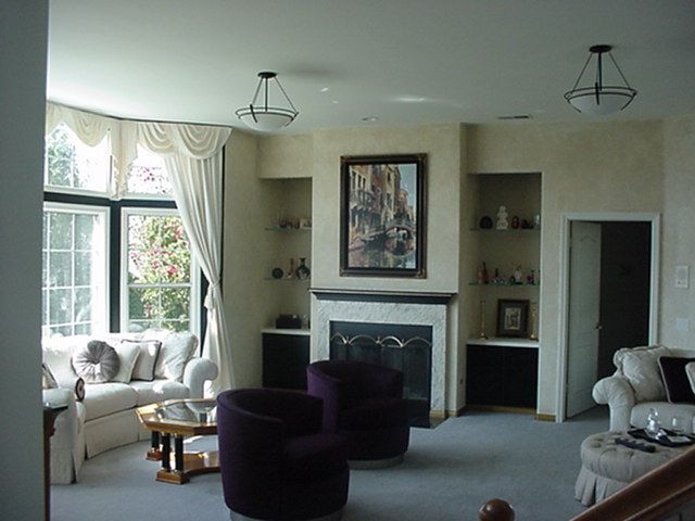 A living room with purple chairs and a fireplace