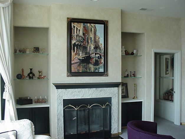 A living room with a fireplace and a painting on the wall above it
