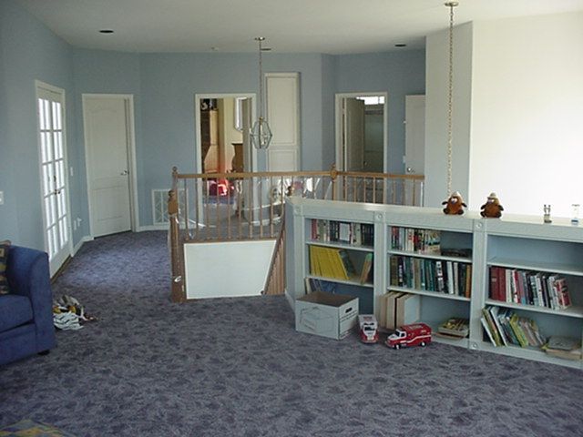 A living room with purple carpet and shelves full of books