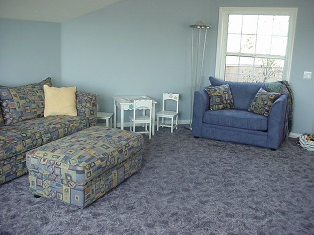 A living room with purple carpet and blue furniture