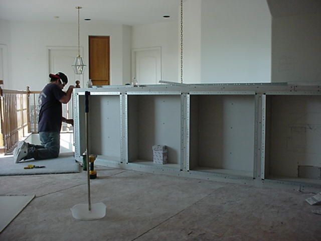 A man is kneeling on the floor working on a shelf