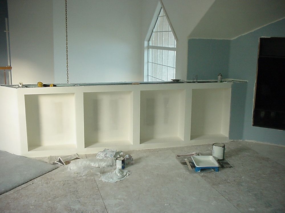 A room with white shelves and a tray of paint on the floor