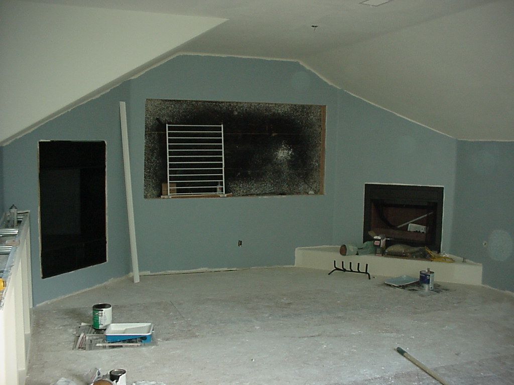 A corner of a room with a fireplace and a window