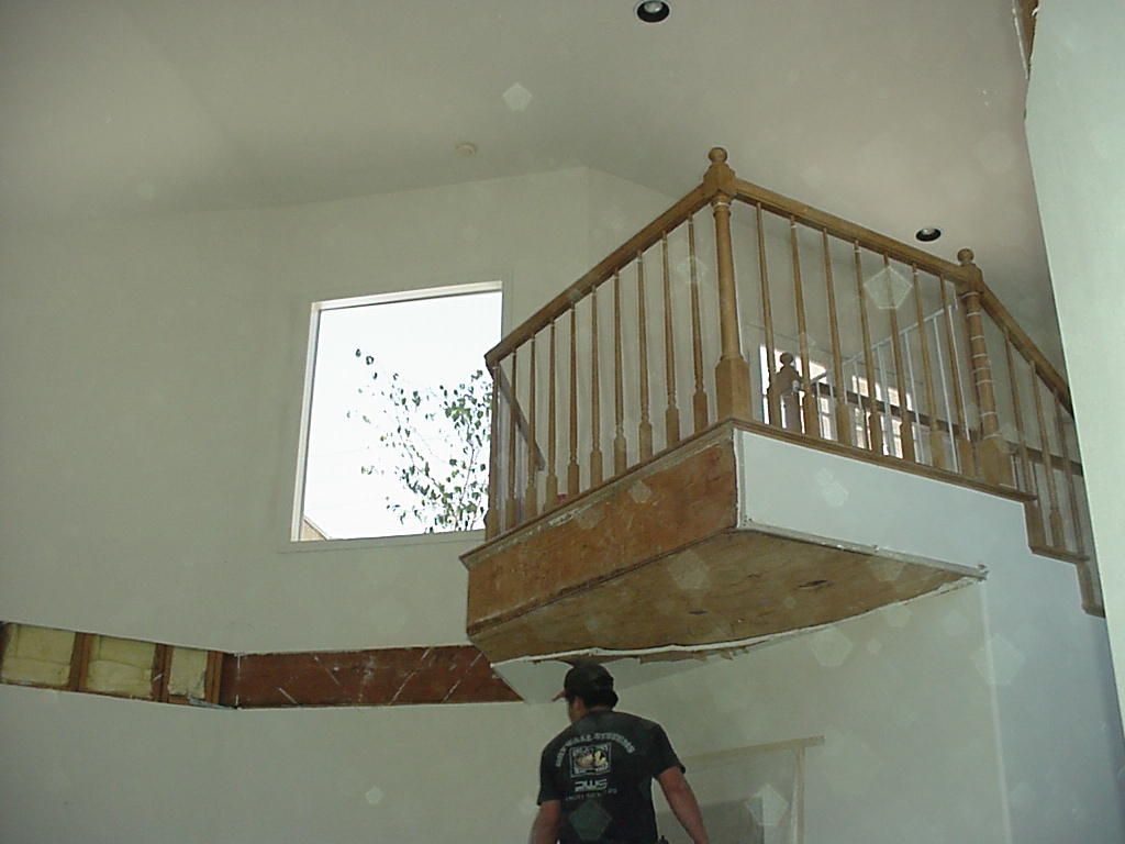A man is standing in a room with a balcony and a window.