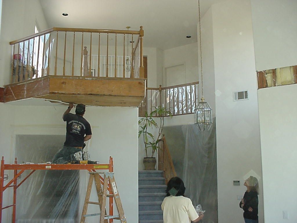 A man standing on a ladder in a room with stairs