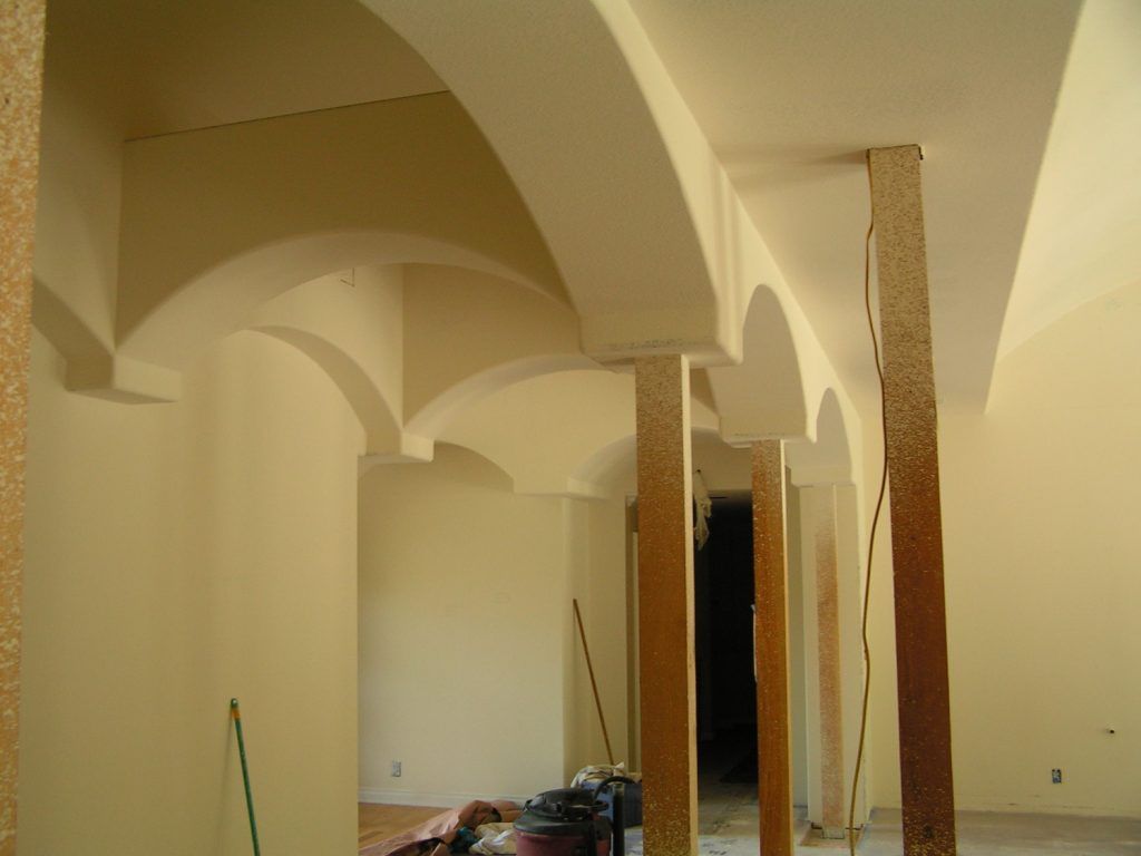 A room with arched ceilings and wooden pillars
